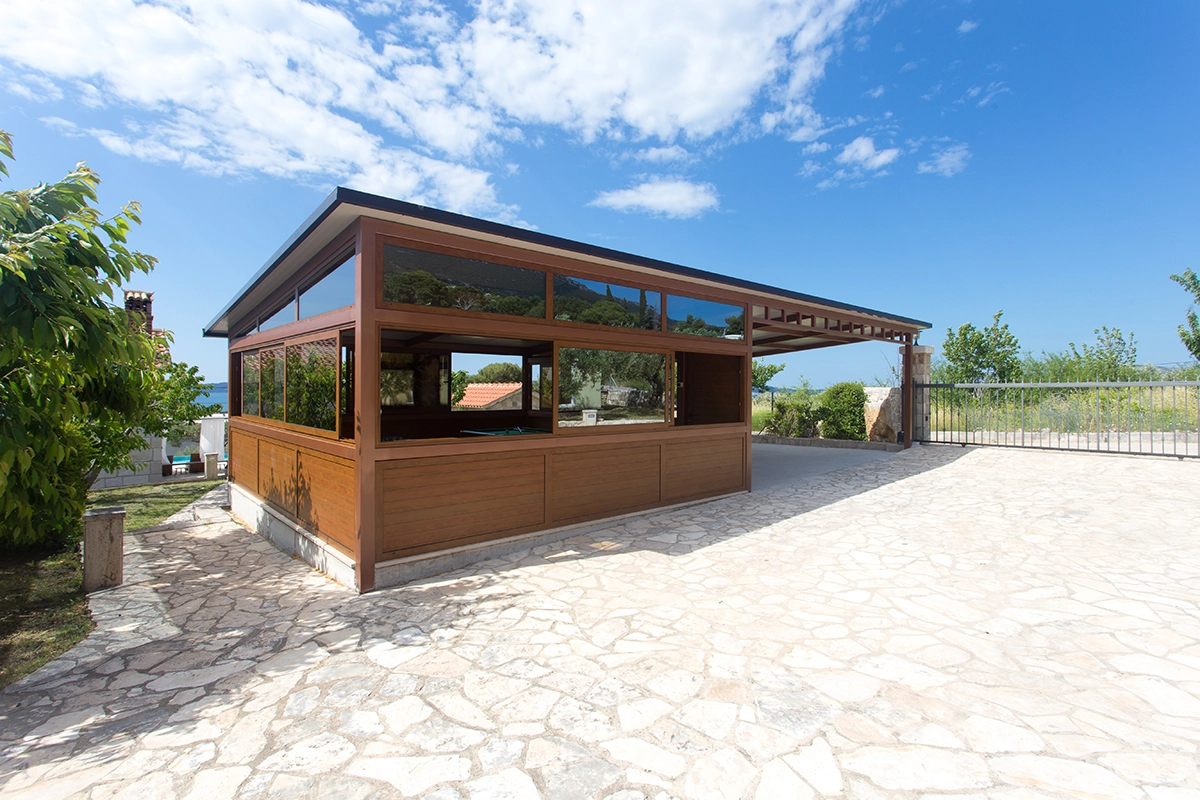 Outdoor wooden structure with two covered parking spaces and an enclosed area for social games and entertainment.